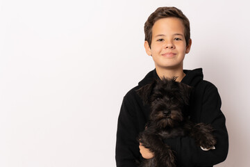 Child boy with a schnauzer puppy isolated over white background.