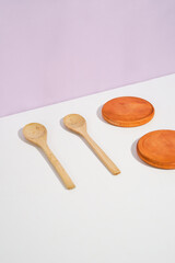 two wooden spoons with two wooden placemats beside. a studio shot of the organic utensils. suitable for advertisement.