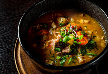 Pichelsteiner meat soup with vegetables in bowl on wooden table background