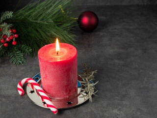 Red Christmas candle and Christmas decorations on a gray background.