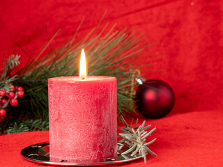 Red Christmas candle and Christmas decorations on a red background.