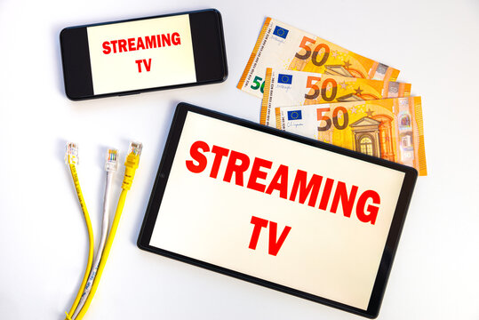 Tablets and smartphones showing the text "streaming tv" on the display, banknotes, data cables, money and electrical plugs. Costs and consumption of streaming TV programs. 
