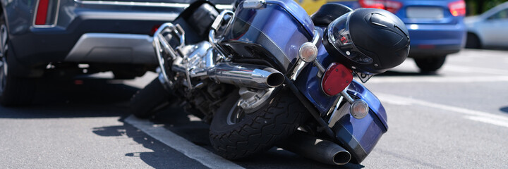 Blue motorcycle lying on road near car closeup