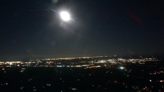 High Altitude Airplane Aerial Over City Skyline With Full Moon And Light Bokeh