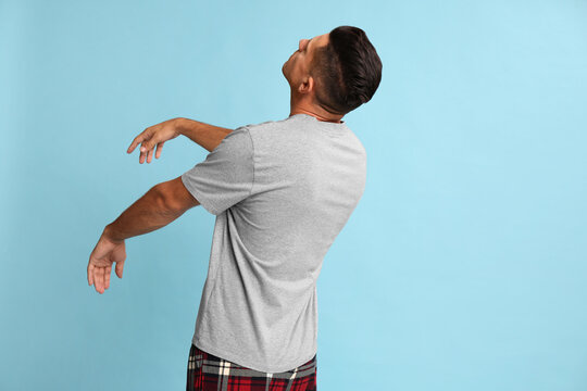 Somnambulist in pajamas on light blue background. Sleepwalking