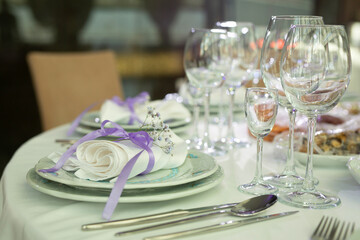 decorated service with plates and glasses on the festive table 