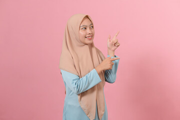 Cheerful muslim woman pointing at copy space