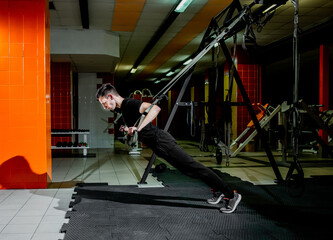Fototapeta na wymiar guy doing exercises on TRX loops in the gym