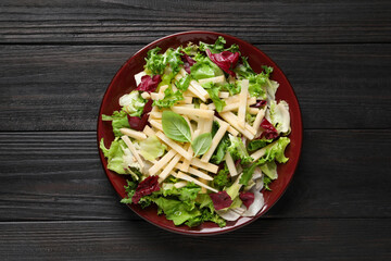 Delicious turnip salad served on black wooden table, top view