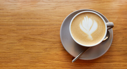 Cup of coffee on wooden table in cafe. Cappuccino or latte in mug. Enjoying time alone
