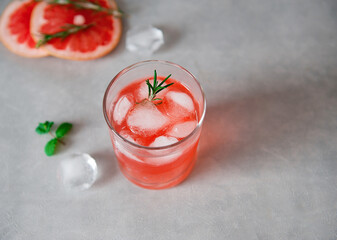 Refreshing drink with grapefruit juice and basil seeds, a sprig of rosemary, ice cubes on a gray background.Detox cocktail. Healthy food. Summer drinks.