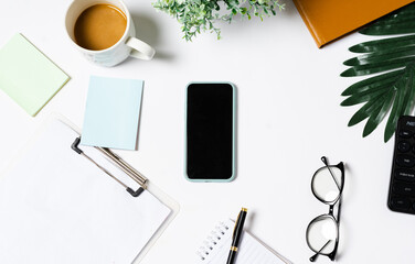 Top view of coffee, book, notebook, pen, keyboard, phone on white background