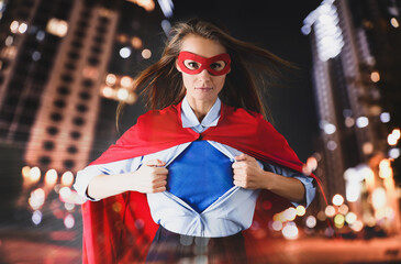 Confident businesswoman wearing superhero costume under suit and beautiful cityscape in night on...