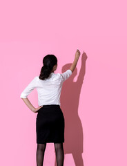 A woman is holding a chalk and writing on a blackboard