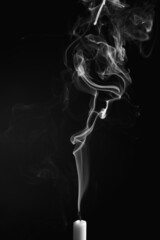 Vertical shot of the smoke of an extinguished candle isolated on a black background
