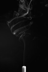 Vertical shot of the smoke of an extinguished candle isolated on a black background