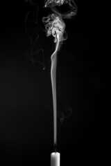 Vertical shot of the smoke of an extinguished candle isolated on a black background