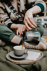 Closeup of a woman pouring black coffee from a glass pot into a mug.