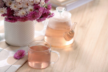 Fresh delicious herbal tea, books and beautiful bouquet on wooden table. Space for text