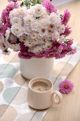 Cup of hot coffee and beautiful bouquet on wooden table
