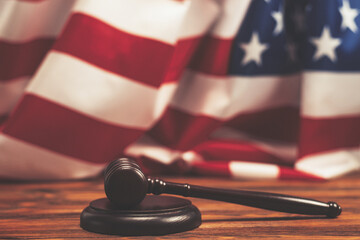 Wooden judge gavel and soundboard on american flag background.