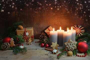 Fourth Advent, four candles are lighted, Christmas decoration and gifts on rustic wooden planks against a dark brown background with copy space, selected focus