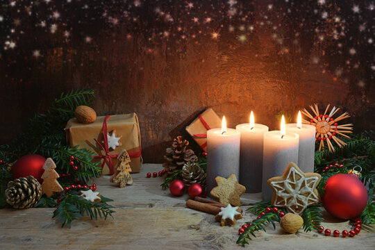 Fourth Advent, four candles are lighted, Christmas decoration and gifts on rustic wooden planks against a dark brown background with copy space, selected focus