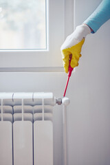 Handyman with gloves fixing and bleeding air from central heating gas radiator system at home.
