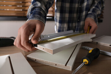 Man assembling furniture at table indoors, closeup