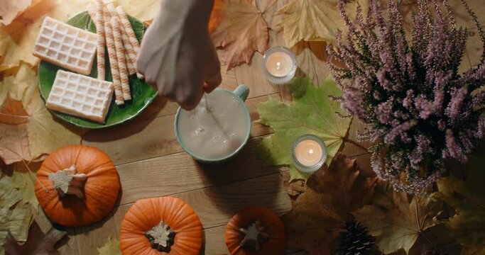 Tabletop video of stiring tea with milk in slow motion. Decorated autumn composition in warm atmosphere with waffles, leaves and tea, 4k 60p Prores HQ