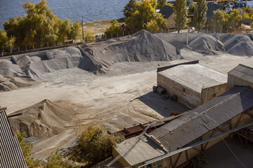 Factory with industrial buildings and piles of building construction sand and dry cement mix