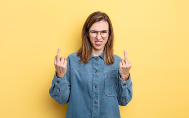 young pretty girl feeling provocative, aggressive and obscene, flipping the middle finger, with a...