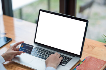 Businesswoman shopping online using a laptop blank white screen and credit card at the office.