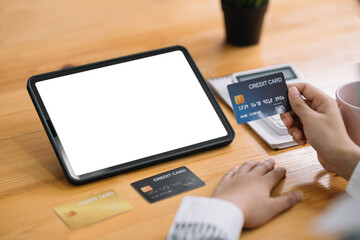 Businesswoman shopping online using a tablet blank white screen and credit card at the office.