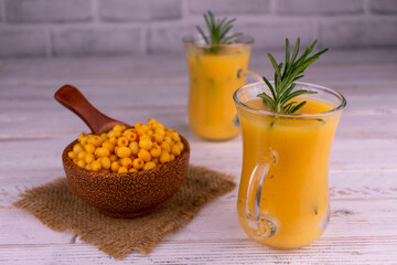 Sea buckthorn smoothie with honey in glass cups on a white wooden background. Vitamin cocktail.