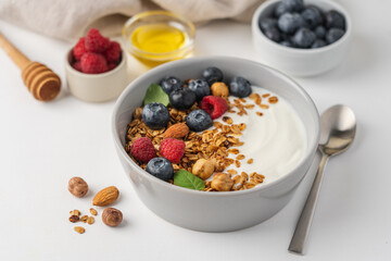 Bowl of yogurt with granola, blueberries, raspberries, almonds, hazelnuts. Homemade breakfast top view