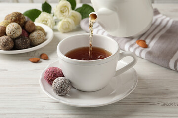 Pouring tea into cup on white wooden table