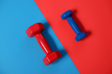 Red and blue dumbbells on an inverted diagonal background. Sport and fitness equipment, dumbbells