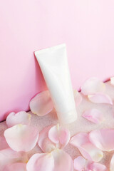 cosmetic tube with face, eye cream or body lotion on pink background with rose petals. Perfumed cosmetic product concept, delicate winter skin care