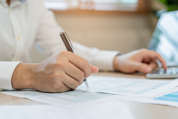 Close up hand of stress asian young employee business man, male calculate tax income and expenses, bills, credit card for payment or payday on table at home office. Financial, finance people concept.