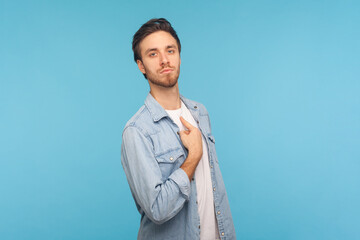 Portrait of man wearing denim shirt, pointing himself and looking with arrogant selfish expression,...