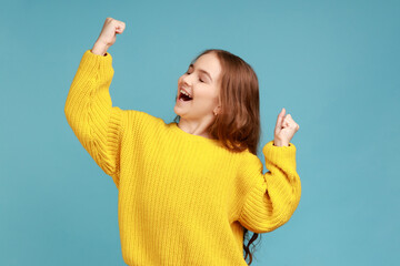 Little girl shouting from happiness, showing yes gesture with raised arms, celebrating victory,...