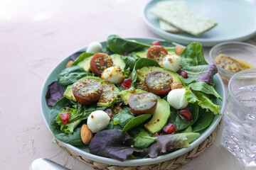 Green leafy salad with avocado, pomegranate, mozzarella balls, cherry tomatoes and almonds. Healthy food. Homemade food