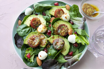 Green leafy salad with avocado, pomegranate, mozzarella balls, cherry tomatoes and almonds. Healthy food. Homemade food