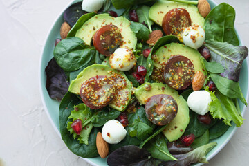 Green leafy salad with avocado, pomegranate, mozzarella balls, cherry tomatoes and almonds. Healthy food. Homemade food