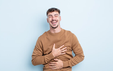 young handsome man laughing out loud at some hilarious joke, feeling happy and cheerful, having fun