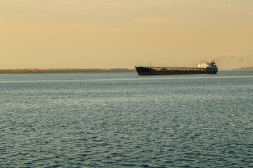A barge in the distance on the water of a large navigable river.