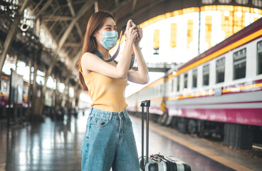 Asian backpack traveler people with camera standing at train station platform and waiting train arrivel, summer holiday travelling or young tourist concept