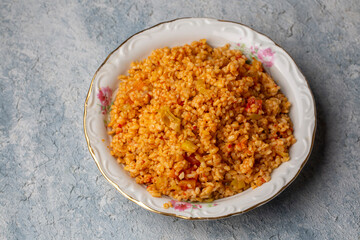 Traditional turkish bulgur pilaf with tomato sause in plate (Turkish name; meyhane pilavi)