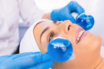 Close up portrait of beautiful woman with towel on head undergoes massaging face procedure by a...